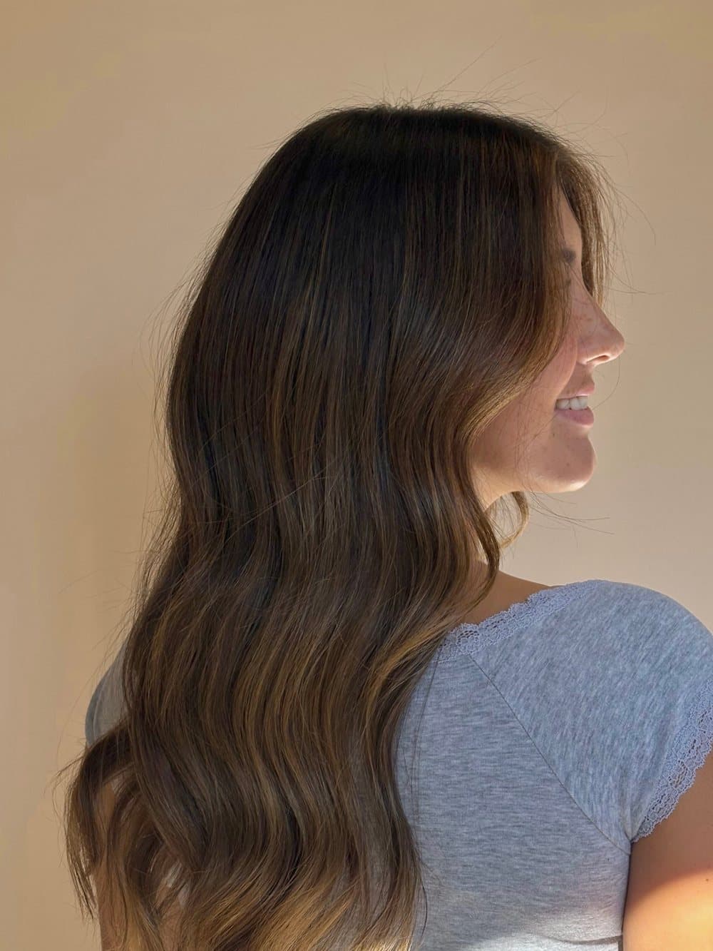 Brunette lived-in balayage with loose waves, seen from the side